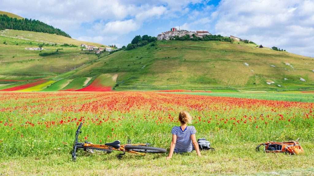 18 Gorgeous Mountain Villages That Feel Like a Hidden World 12 Castelluccio Italy women relax chill travel bike