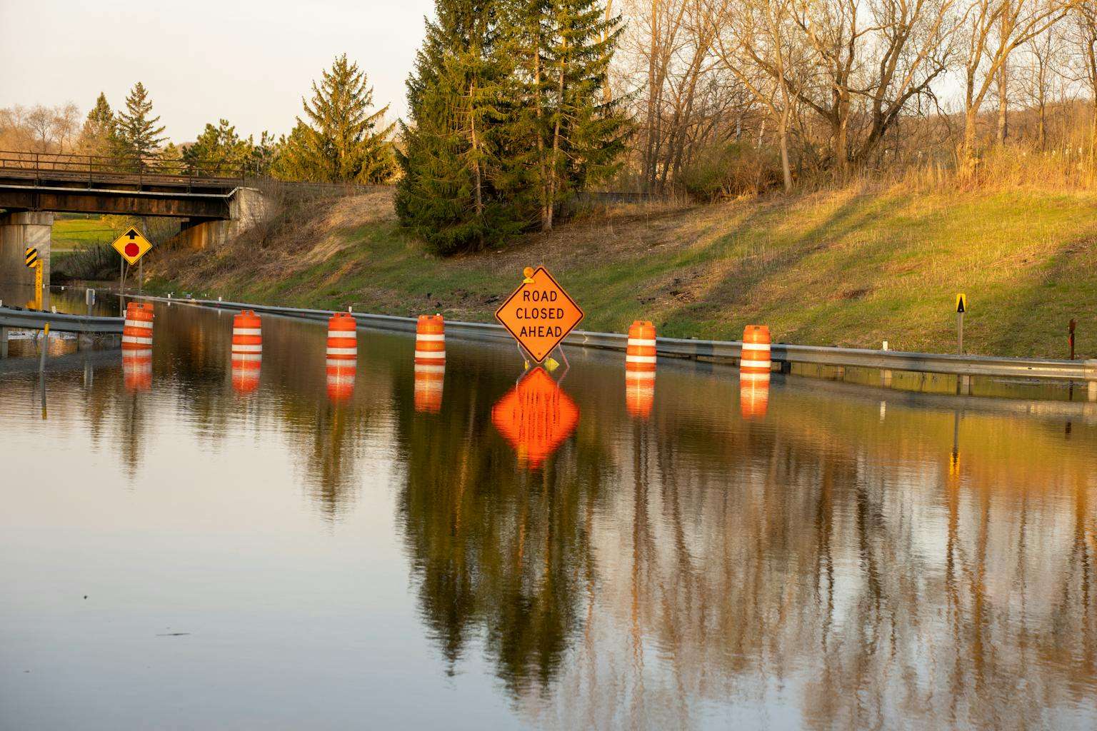 20 American Disaster Towns Forever Marked by One Terrifying Day 3 A flooded road with warning signs indicating 'Road Closed Ahead' due to water overflow.