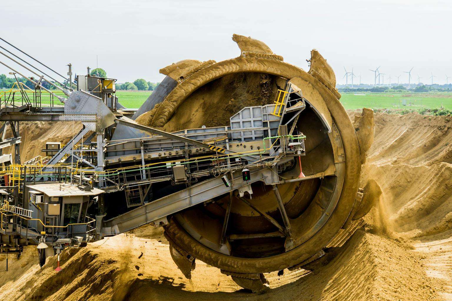 20 American Disaster Towns Forever Marked by One Terrifying Day 13 A large bucket wheel excavator working in an open pit mine against a green landscape.