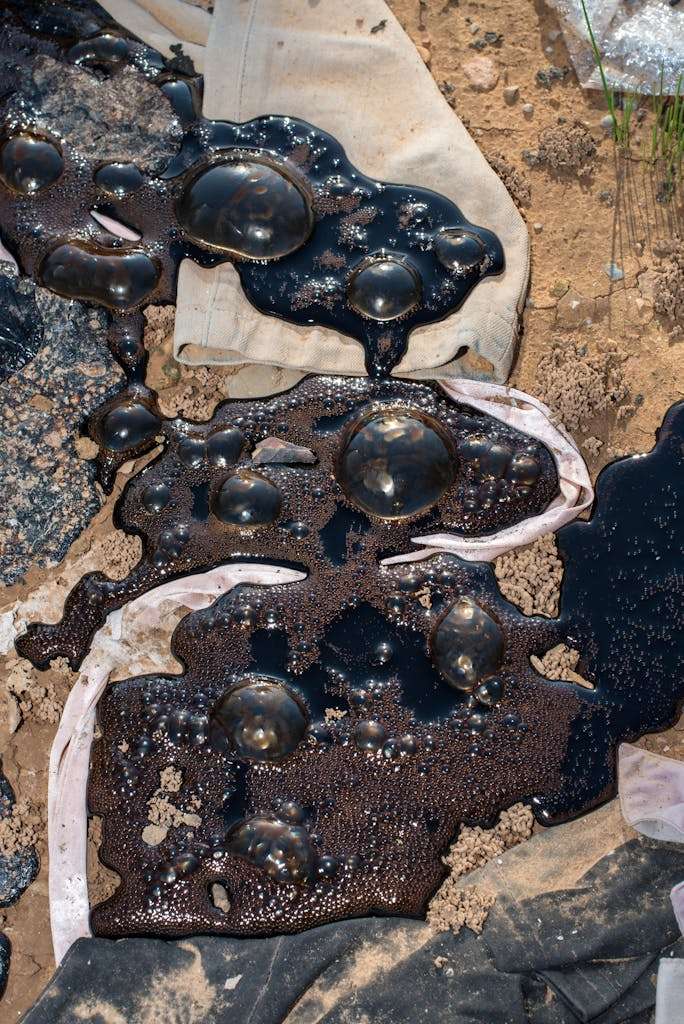 20 American Disaster Towns Forever Marked by One Terrifying Day 20 Close-up of dark oil spill on textured ground with fabric. Environmental impact.